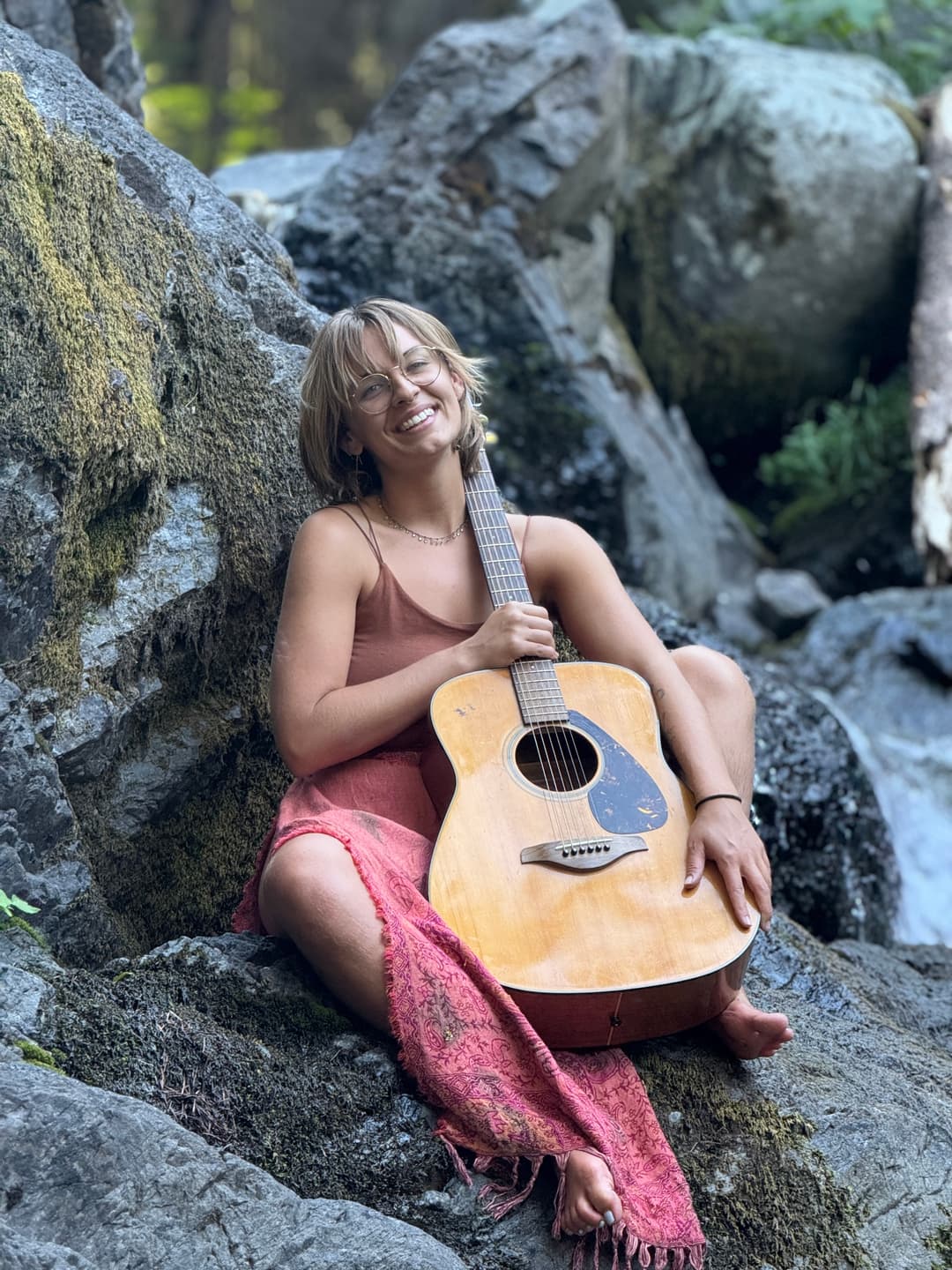 Flow playing guitar on mossy river rocks